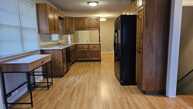 kitchen featuring sink, light hardwood / wood-style flooring, and black appliances