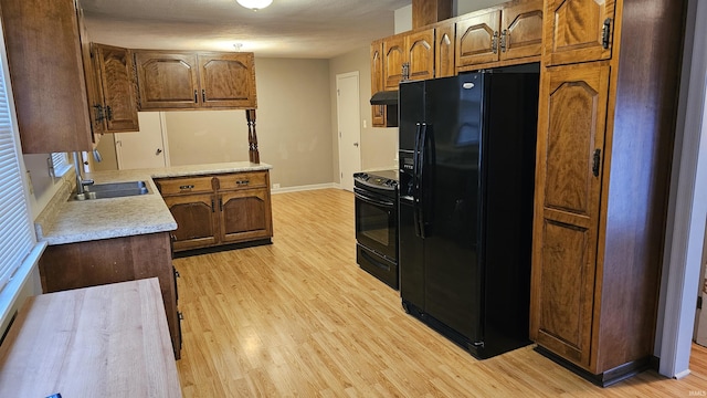 kitchen with sink, black appliances, and light hardwood / wood-style floors