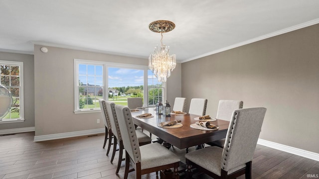 dining space with dark wood-type flooring, ornamental molding, and a chandelier