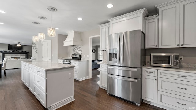 kitchen with custom exhaust hood, decorative light fixtures, a center island, stainless steel appliances, and white cabinets