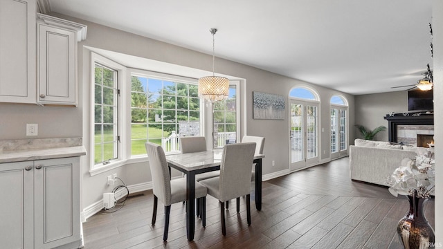 dining space with plenty of natural light, dark wood-type flooring, and ceiling fan with notable chandelier