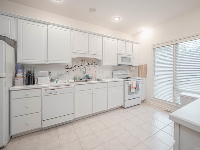 kitchen featuring light tile patterned flooring, tasteful backsplash, white cabinetry, sink, and white appliances