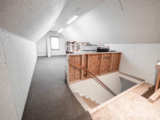 additional living space featuring lofted ceiling, carpet floors, and a textured ceiling