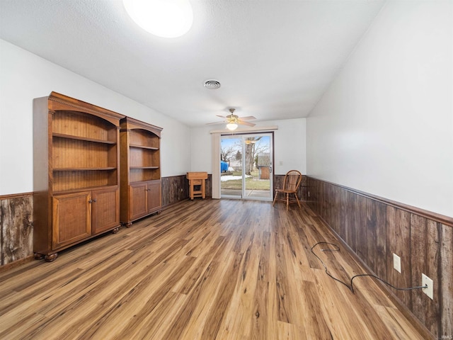 interior space featuring hardwood / wood-style flooring, ceiling fan, and wooden walls