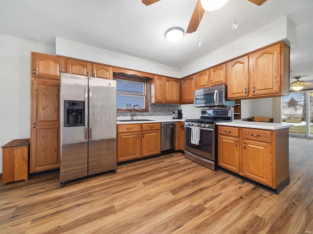 kitchen with sink, hardwood / wood-style flooring, ceiling fan, appliances with stainless steel finishes, and kitchen peninsula