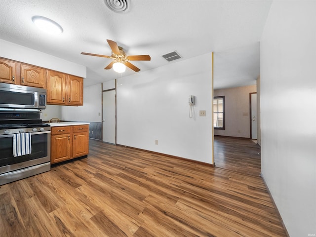 kitchen featuring a textured ceiling, wood-type flooring, stainless steel appliances, and ceiling fan