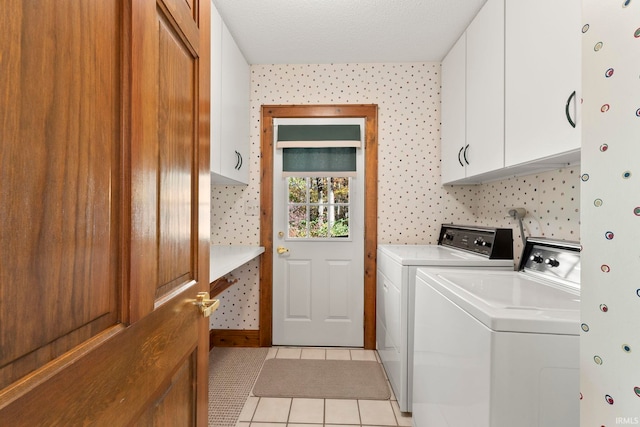 laundry room with cabinets, washer and dryer, light tile patterned floors, and a textured ceiling