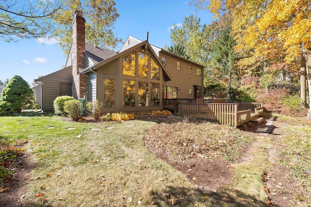 rear view of house featuring a wooden deck and a lawn