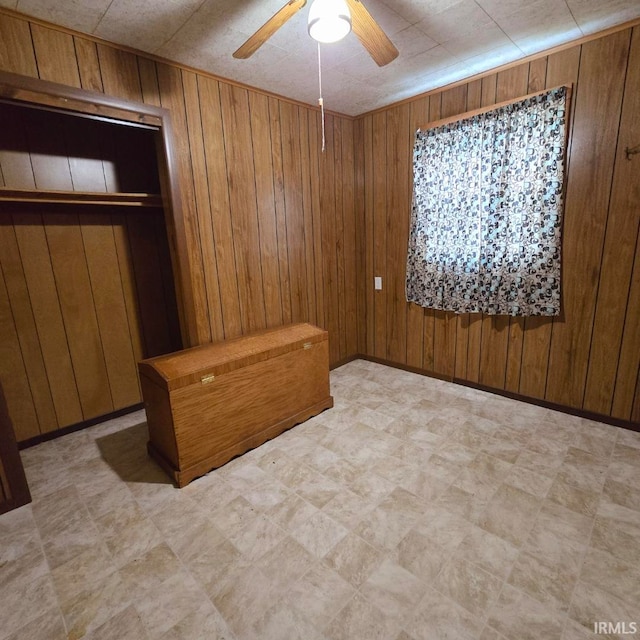 spare room featuring ceiling fan and wood walls