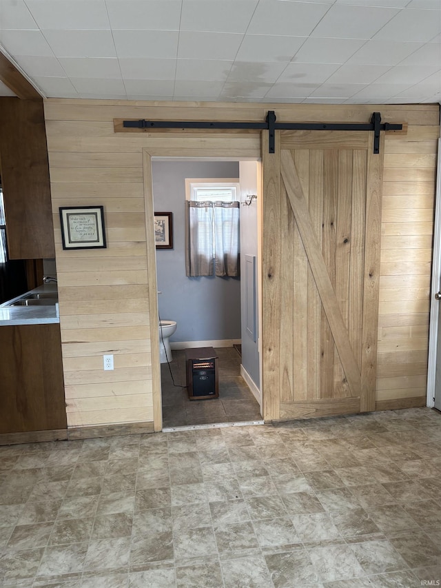 interior space featuring a barn door, sink, and wood walls