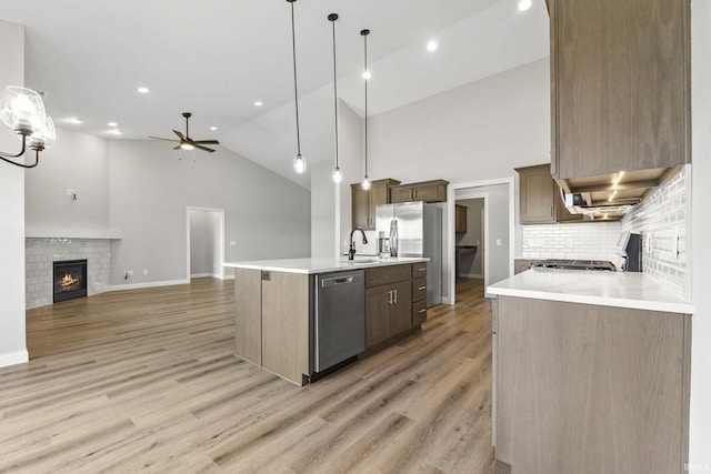 kitchen with sink, a kitchen island with sink, hanging light fixtures, hardwood / wood-style floors, and stainless steel appliances