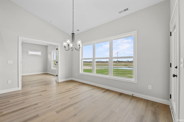 unfurnished dining area featuring an inviting chandelier, vaulted ceiling, and light wood-type flooring