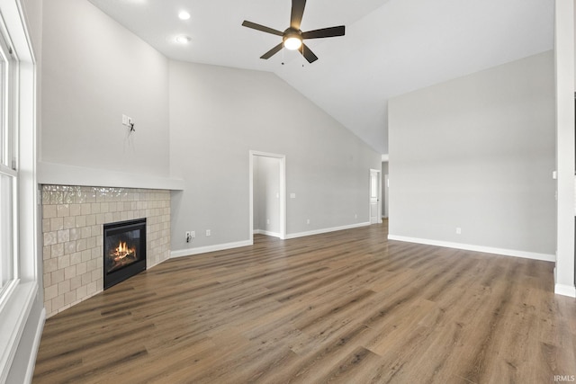 unfurnished living room with dark hardwood / wood-style flooring, high vaulted ceiling, ceiling fan, and a fireplace