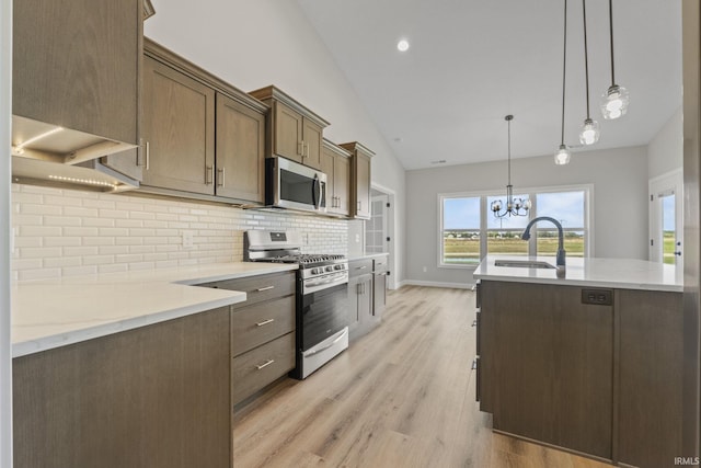 kitchen featuring sink, decorative light fixtures, appliances with stainless steel finishes, light stone countertops, and backsplash