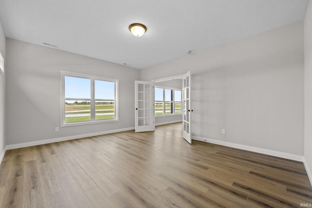 spare room with hardwood / wood-style flooring and french doors