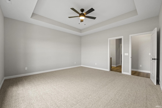 unfurnished bedroom with ceiling fan, a raised ceiling, and carpet floors