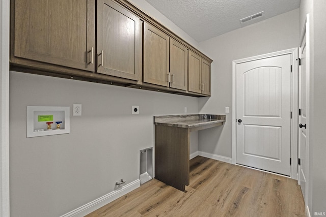 clothes washing area featuring light hardwood / wood-style flooring, electric dryer hookup, cabinets, washer hookup, and a textured ceiling