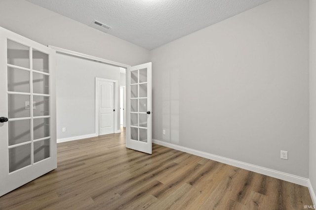 empty room featuring wood-type flooring, a textured ceiling, and french doors