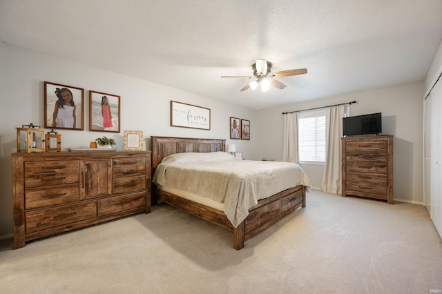 bedroom featuring ceiling fan, light carpet, and a textured ceiling