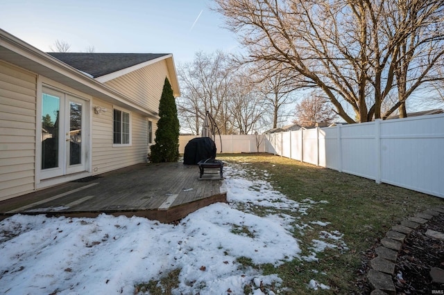 yard covered in snow with a wooden deck and an outdoor fire pit