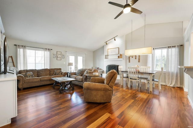 living room featuring vaulted ceiling, a brick fireplace, plenty of natural light, and dark hardwood / wood-style flooring