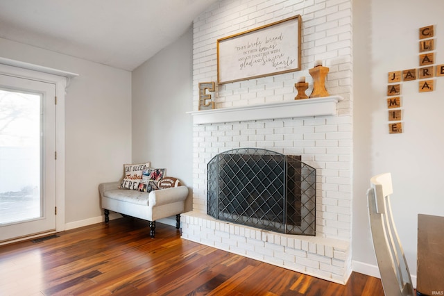 living room featuring vaulted ceiling, dark wood-type flooring, and a fireplace