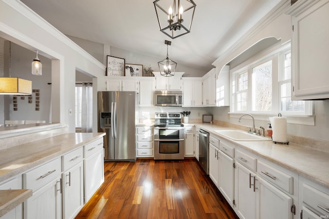 kitchen with hanging light fixtures, appliances with stainless steel finishes, sink, and white cabinets