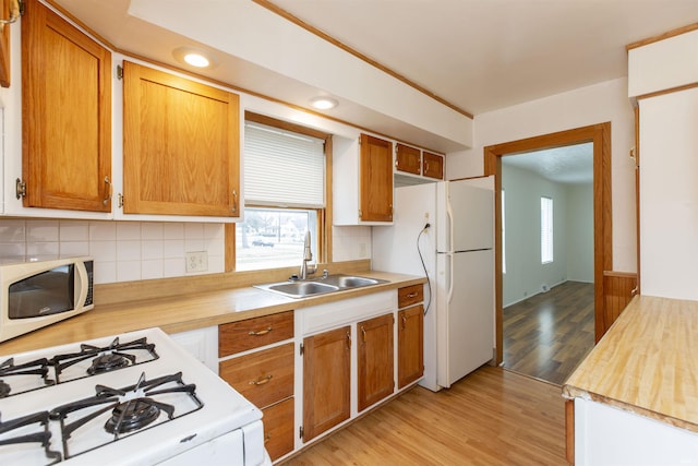 kitchen with sink, white appliances, light hardwood / wood-style floors, and decorative backsplash