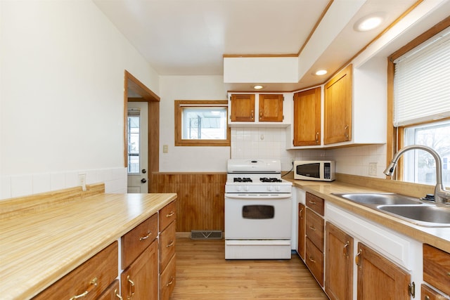 kitchen featuring sink, backsplash, white appliances, and light hardwood / wood-style flooring