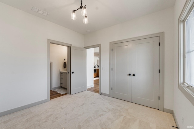 unfurnished bedroom with light colored carpet, ensuite bath, and a closet