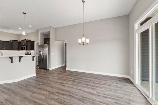 kitchen with appliances with stainless steel finishes, hardwood / wood-style floors, pendant lighting, a kitchen breakfast bar, and a healthy amount of sunlight