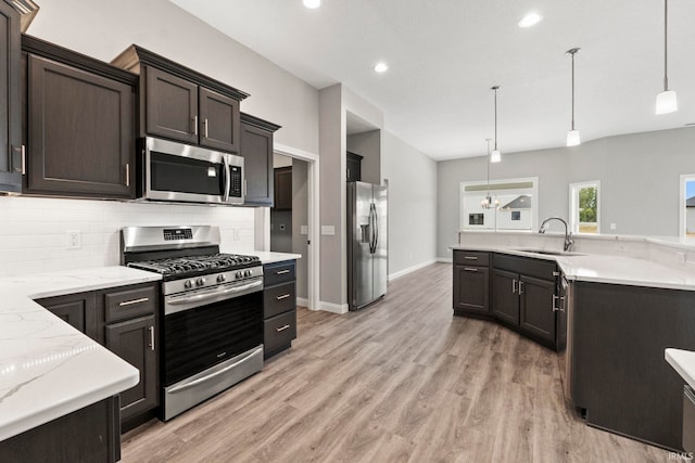 kitchen featuring sink, light hardwood / wood-style flooring, hanging light fixtures, stainless steel appliances, and tasteful backsplash