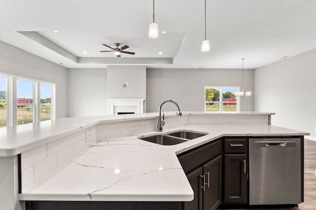 kitchen with stainless steel dishwasher, a tray ceiling, decorative light fixtures, and sink