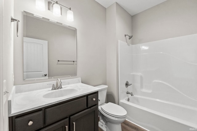 full bathroom with  shower combination, toilet, hardwood / wood-style floors, and vanity