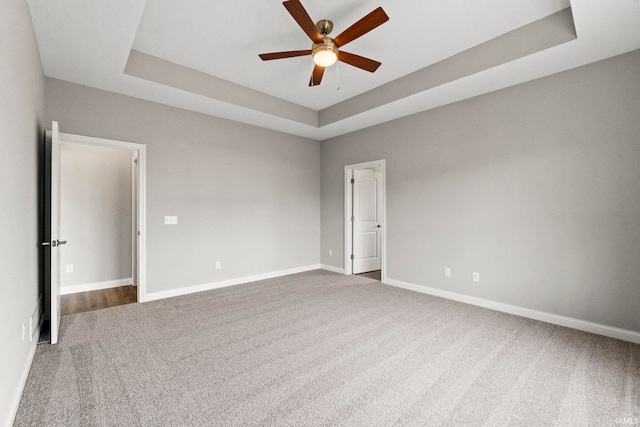 unfurnished room featuring ceiling fan, a raised ceiling, and carpet floors