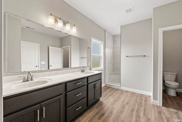 bathroom with vanity, wood-type flooring, toilet, and a tile shower