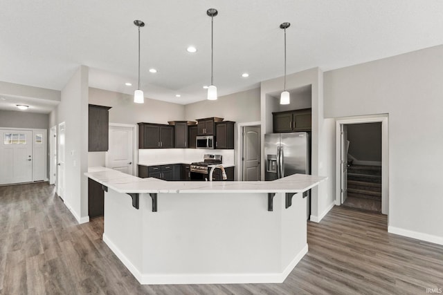 kitchen with stainless steel appliances, a large island, decorative light fixtures, and a breakfast bar area