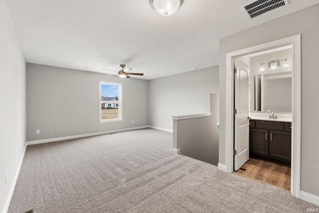 carpeted empty room with ceiling fan, sink, and a textured ceiling