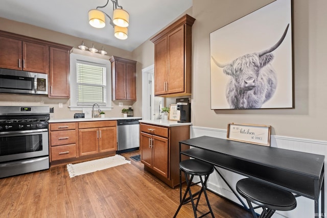 kitchen featuring sink, hardwood / wood-style flooring, an inviting chandelier, stainless steel appliances, and decorative light fixtures