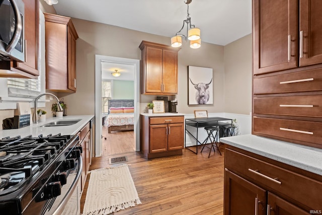 kitchen featuring pendant lighting, sink, a notable chandelier, stainless steel appliances, and light hardwood / wood-style flooring