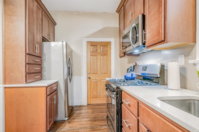 kitchen featuring appliances with stainless steel finishes, sink, and light hardwood / wood-style flooring