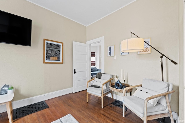 living area featuring crown molding and dark hardwood / wood-style flooring