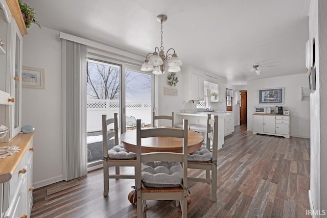 dining area with dark hardwood / wood-style floors, a wealth of natural light, and a notable chandelier