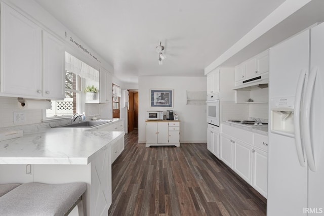 kitchen with sink, white appliances, dark wood-type flooring, white cabinets, and decorative backsplash