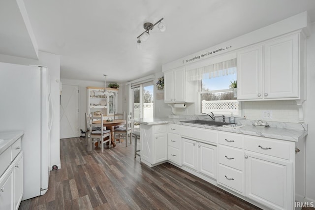 kitchen with sink, white refrigerator, white cabinets, dark hardwood / wood-style flooring, and decorative backsplash