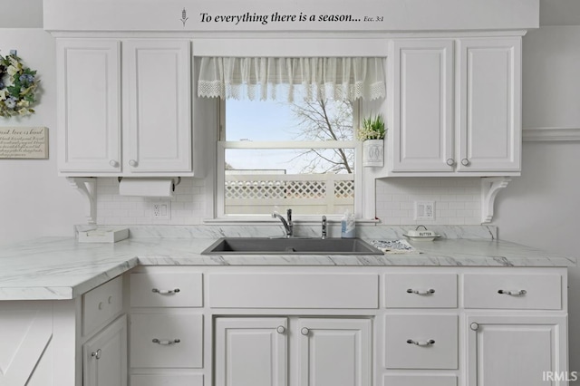 kitchen featuring tasteful backsplash, sink, and white cabinets