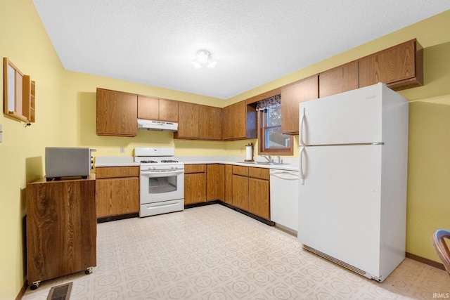 kitchen with sink, white appliances, and a textured ceiling