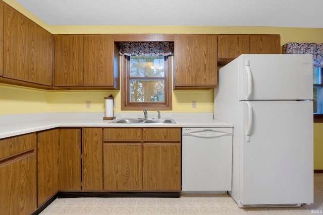 kitchen featuring white appliances, sink, and a textured ceiling