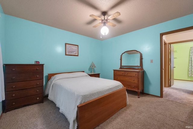 bedroom with ceiling fan, light colored carpet, and a textured ceiling