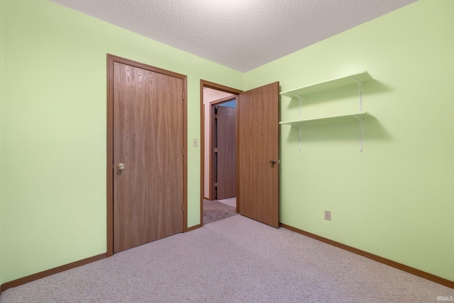 unfurnished bedroom featuring light colored carpet, a closet, and a textured ceiling